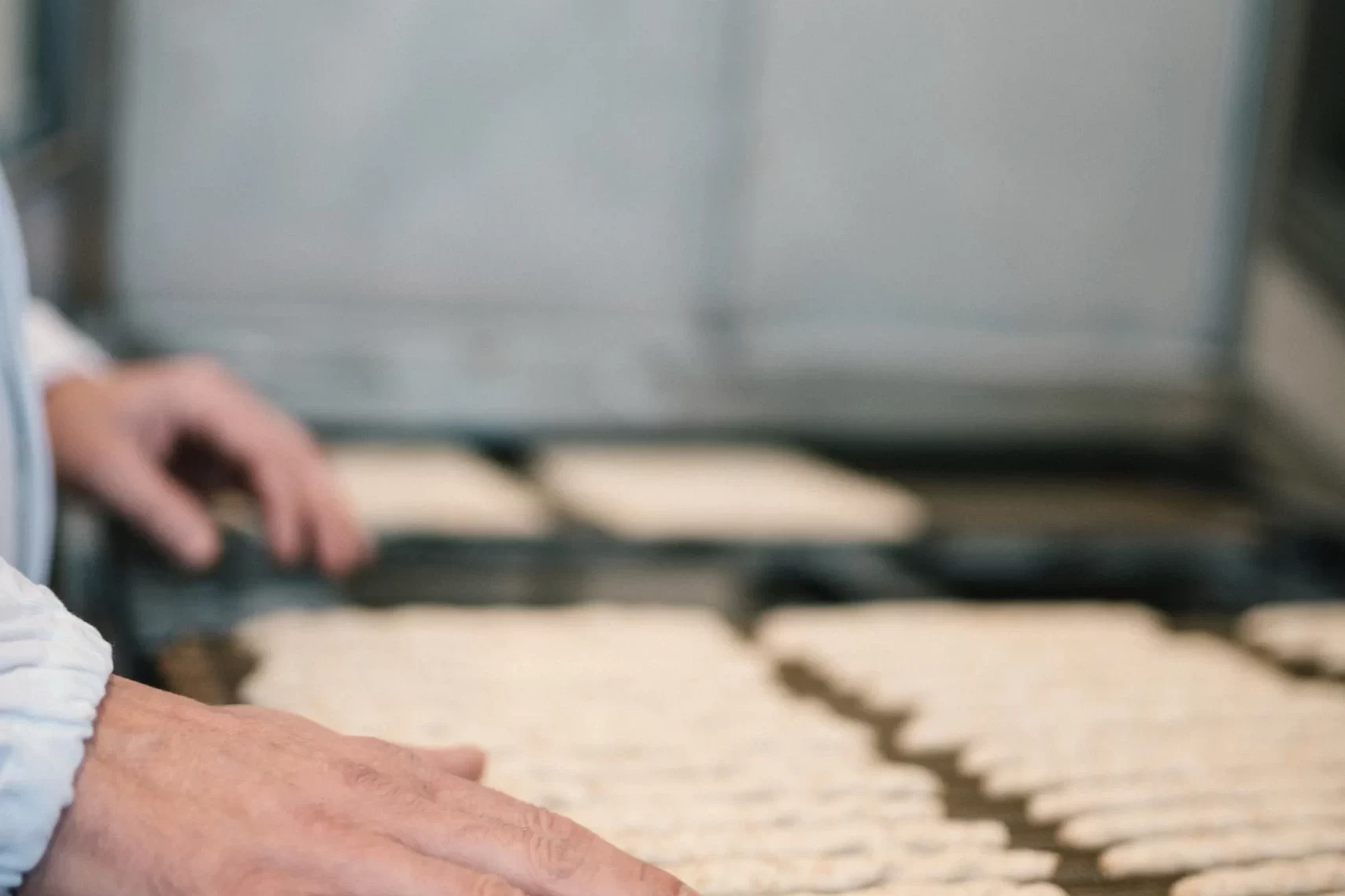 Uomo che sistema piccoli pezzi di pasta su una teglia per la cottura