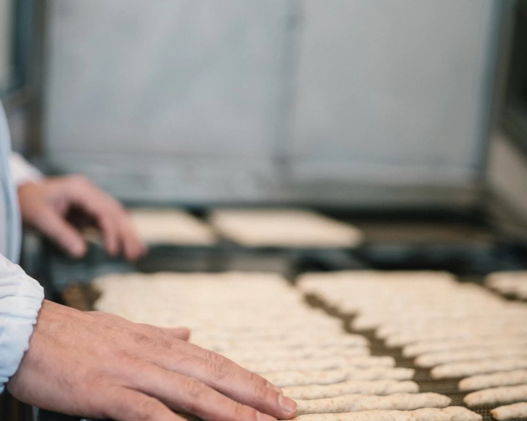 Uomo che sistema piccoli pezzi di pasta su una teglia per la cottura