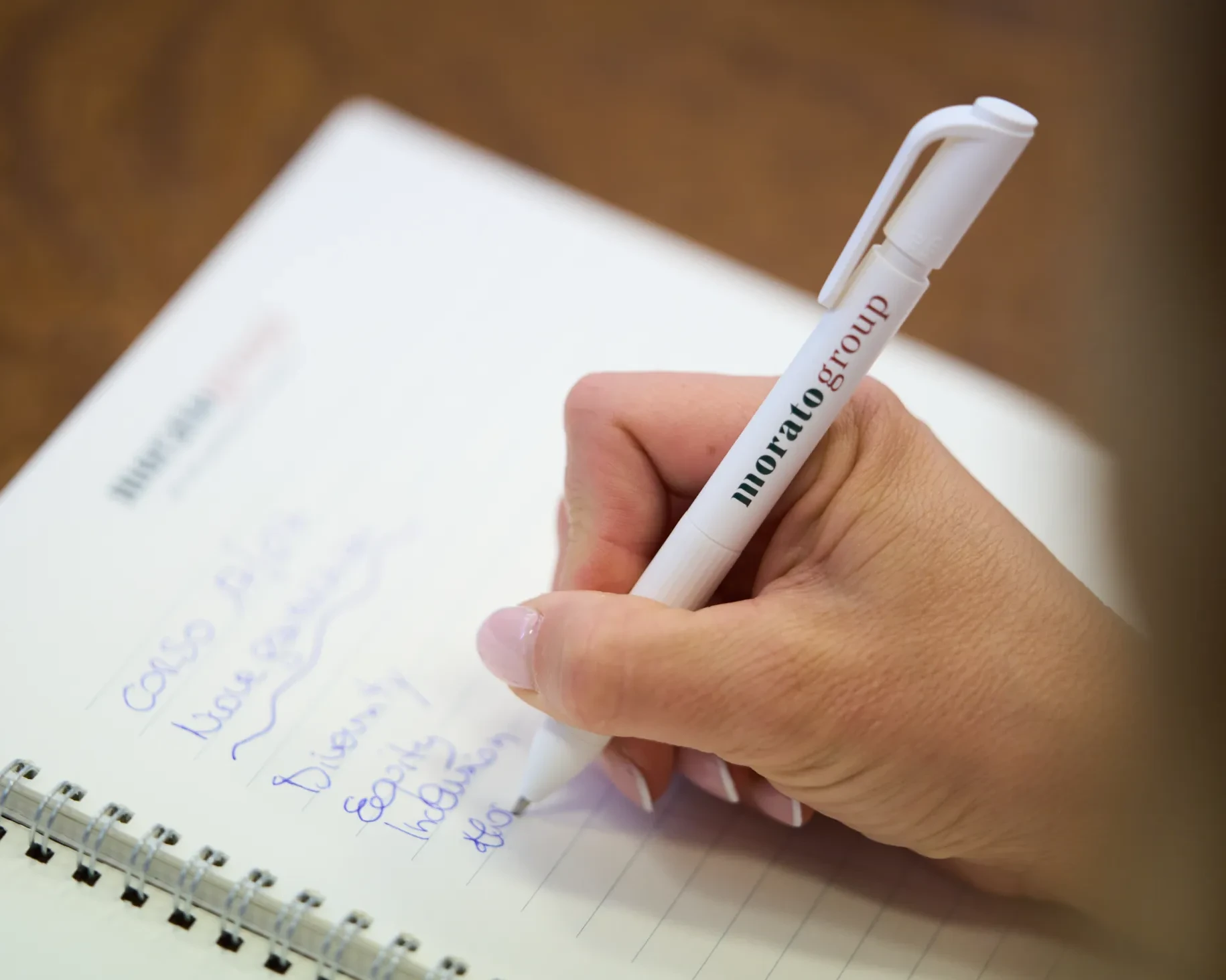 Una mano scrive note su un quaderno con una penna su un tavolo di legno