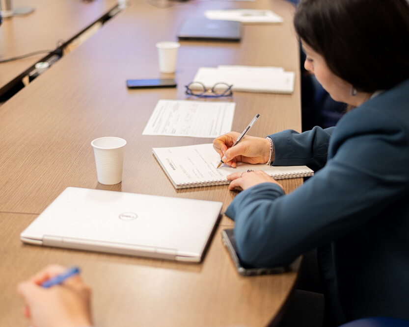 Donna che prende appunti durante una riunione di lavoro in un ambiente professionale