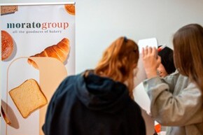 Stand promozionale del Morato Group con prodotti da forno e visitatori che interagiscono