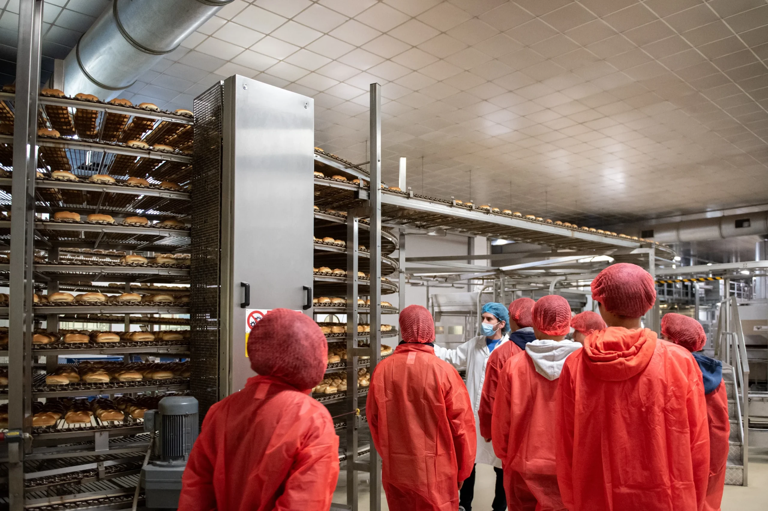 Gruppo di persone in abbigliamento protettivo visitano un impianto di produzione alimentare